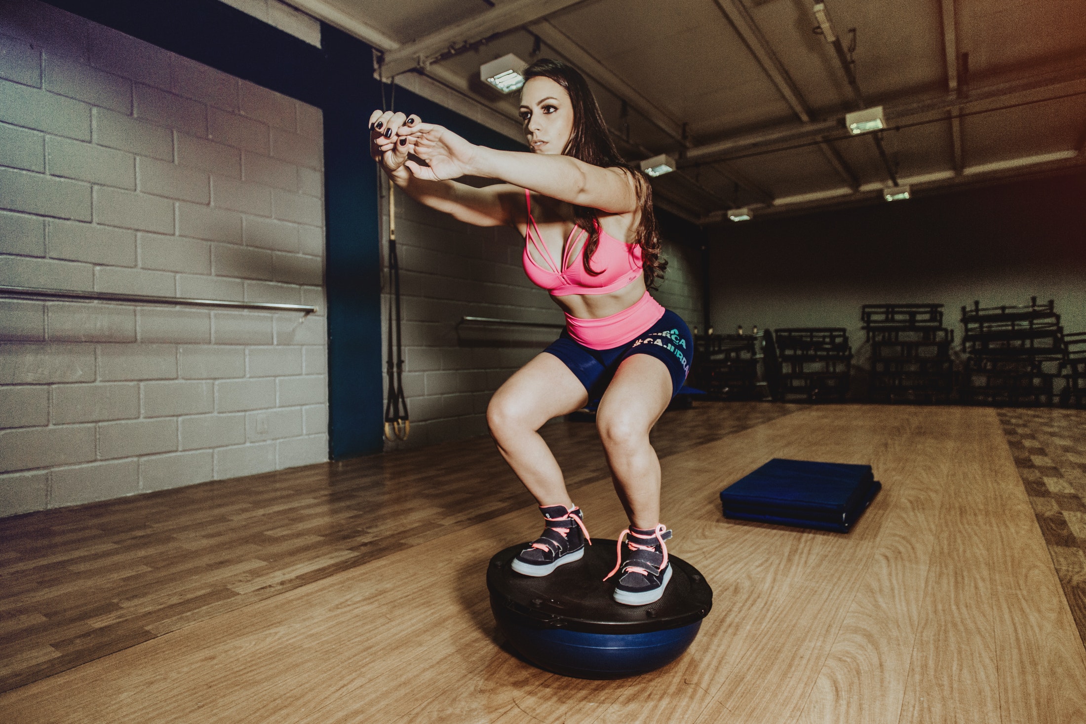 Sporty woman squatting on bosu ball in gym